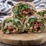 WW-Friendly Chicken Caesar Wrap A lighter take on a classic favorite, this WW-Friendly Chicken Caesar Wrap is a high-protein, satisfying lunch made with tender chicken, crispy lettuce, creamy cottage cheese, and Caesar-inspired flavors wrapped in a soft whole wheat tortilla. Recipe Card WW-Friendly Chicken Caesar Wrap (Lower Points Version) A deliciously balanced chicken wrap with classic Caesar salad flavors, extra protein, and a lighter ingredient combination that fits easily into a WW-friendly meal plan. Prep Time: 10 minutes Cook Time: 15 minutes Total Time: 25 minutes Servings: 2 wraps Dietary Highlights: WW-friendly High-protein Lower-point meal option High in lean protein Meal-prep friendly Ingredients 220 g chicken breast 1 bacon medallion 1½ heads romaine lettuce, chopped 1 portion Caesar salad dressing 2 whole wheat tortilla wraps 100 g fat-free cottage cheese 100 g cucumber, diced 2 tomatoes, diced 3 g Parmesan cheese, grated Instructions Cook the chicken breast and bacon medallion until fully cooked. Chop the chicken and bacon into small bite-sized pieces. Chop the romaine lettuce and toss with Caesar salad dressing. Warm the whole wheat tortillas briefly until soft and flexible. Spread half of the cottage cheese evenly over each tortilla. Add dressed lettuce, chicken, bacon, cucumber, tomatoes, and Parmesan. Roll each tortilla tightly, slice in half, and serve. Recipe Notes Use freshly cooked chicken for the best texture and flavor. Cottage cheese adds creaminess and extra protein while helping reduce the need for heavier sauces. For meal prep, keep the filling separate from tortillas until ready to eat to prevent sogginess. Adjust the Caesar dressing amount based on your personal WW points allowance. A Lighter Caesar Wrap That Still Feels Indulgent Classic Caesar wraps are usually packed with creamy dressing, large portions of cheese, and calorie-dense ingredients. This version keeps everything you love about the original while making a few smart swaps that help create a more balanced meal. This WW-Friendly Chicken Caesar Wrap combines juicy chicken breast, crispy romaine lettuce, smoky bacon, and a creamy cottage cheese layer for a wrap that feels satisfying instead of restrictive. It is perfect for busy lunches, quick dinners, or preparing ahead for a grab-and-go meal. The best part? You still get the familiar Caesar flavors: savory chicken, crunchy lettuce, salty Parmesan, and creamy dressing in every bite. How to Make the WW-Friendly Chicken Caesar Wrap Cook the Chicken and Bacon Start by cooking the chicken breast and bacon medallion until completely cooked through. The chicken should be tender and juicy, while the bacon should add a savory, smoky flavor throughout the wrap. For the best results, season the chicken lightly before cooking. Simple seasonings like black pepper, garlic powder, paprika, or Italian seasoning can add extra flavor without significantly changing the recipe. Once cooked, allow the chicken to rest for a few minutes before chopping. This helps keep the juices inside instead of losing moisture during cutting. Tip: Avoid overcooking chicken breast because it can become dry. Cooking just until done keeps the wrap much more enjoyable. Prepare the Caesar Lettuce Filling Chop the romaine lettuce into thin pieces so it distributes evenly throughout each wrap. Toss the lettuce with the Caesar dressing until lightly coated. The goal is not to soak the lettuce but to add enough dressing for flavor while keeping the tortilla firm. Romaine lettuce is ideal for this recipe because it stays crisp and provides the classic Caesar salad texture. Tip: If preparing ahead, store the dressed lettuce separately and mix just before assembling. Build the Wraps Warm the tortillas briefly before assembling. A slightly warm tortilla is softer, easier to roll, and less likely to crack. Spread the fat-free cottage cheese across each tortilla. This step creates a creamy base while adding extra protein to the wrap. Next, layer the Caesar lettuce mixture, chopped chicken, bacon, cucumber, tomatoes, and Parmesan. Try not to overfill the tortillas. Too many ingredients can make rolling difficult and cause the filling to spill out. Fold the sides inward, roll tightly from one end, and slice before serving. Ingredient Details and Substitution Tips Chicken Breast Chicken breast is the main protein source in this wrap. It is naturally lean, filling, and works well with bold flavors like Caesar dressing and Parmesan. For the best texture, choose fresh chicken breast and avoid cooking it at excessively high temperatures. Substitutions: Cooked turkey breast can replace chicken. Rotisserie chicken works for a faster version. Grilled chicken adds a smoky flavor. Fat-Free Cottage Cheese Cottage cheese is one of the ingredients that makes this wrap unique. Instead of relying only on dressing or mayonnaise-based sauces, cottage cheese adds creaminess and boosts protein. If you prefer a smoother texture, blend the cottage cheese before spreading it onto the tortillas. Substitutions: Low-fat cottage cheese Plain Greek yogurt Light cream cheese spread Whole Wheat Tortillas Whole wheat tortillas provide structure and additional fiber compared with traditional white tortillas. Choose tortillas that are large enough to hold the filling without tearing. Substitutions: High-protein wraps Lower-carb tortillas Gluten-free wraps if needed Romaine Lettuce Romaine creates the classic Caesar salad experience. Its crunchy texture holds up well inside wraps. For maximum freshness, use crisp green leaves and remove any wilted outer pieces. Caesar Dressing Caesar dressing provides the signature flavor. Since dressing can vary significantly in calories and WW points, choose a lighter option if needed. You can also control the amount used by lightly coating the lettuce instead of adding extra sauce. Bacon Medallion A small amount of bacon adds a lot of flavor. Using a bacon medallion keeps the smoky taste while maintaining a lighter profile. Substitutions: Turkey bacon Extra chicken Smoked chicken pieces Recipe Variations and Serving Suggestions Extra Protein Chicken Caesar Wrap For an even higher-protein version, increase the chicken breast to 300 g and add an extra 50 g of cottage cheese. The wrap will become more filling without needing larger portions. Mediterranean Chicken Wrap Swap Caesar dressing for a light yogurt-based dressing and add: 30 g diced peppers Fresh herbs A sprinkle of oregano This creates a fresh Mediterranean-inspired variation. Spicy Chicken Caesar Wrap Add: 1 teaspoon hot sauce Chili flakes Spicy seasoning on the chicken The heat pairs well with the creamy ingredients. Vegetarian Caesar Wrap Replace chicken and bacon with: Grilled mushrooms Roasted chickpeas Extra vegetables Use vegetarian Caesar dressing if needed. Gluten-Free Version To make this recipe gluten-free: Use certified gluten-free tortillas. Check that your dressing and seasonings are gluten-free. The filling itself can easily fit a gluten-free eating pattern. Serving Suggestions This wrap makes a complete lunch on its own, but you can pair it with lighter sides for a larger meal. Good options include: Fresh fruit Vegetable sticks with yogurt dip A small side salad Roasted vegetables A cup of soup For drinks, sparkling water with lemon, iced tea, or a light coffee pairs well with the fresh Caesar flavors. Storage and Make-Ahead Instructions Refrigerator Storage Prepared wraps are best enjoyed fresh, but they can be stored for short periods. Wrap assembled leftovers tightly in foil or reusable food wrap and refrigerate for up to 24 hours. For the best texture, store: Chicken separately Lettuce mixture separately Tortillas separately Then assemble when ready. Meal Prep Tips This recipe works well for meal preparation. Prepare the following ahead: Cook and chop chicken Cook bacon Dice vegetables Portion cottage cheese Store ingredients separately in airtight containers. When ready to eat, assemble the wrap fresh in just a few minutes. Freezing Freezing is not recommended because lettuce, cucumber, and cottage cheese can change texture after thawing. Nutrition Information Approximate nutrition per wrap: Calories: 350–400 kcal Protein: 35–40 g Carbohydrates: 30–35 g Fat: 10–14 g Nutrition will vary depending on the tortilla size and Caesar dressing brand used. Dietary Highlights: High protein Balanced carbohydrates Lower-point friendly option Contains lean protein and vegetables Allergens: Milk (cottage cheese, Parmesan, Caesar dressing) Wheat/gluten (whole wheat tortillas) Eggs and fish may be present depending on Caesar dressing ingredients Frequently Asked Questions Can I use leftover chicken for this wrap? Yes. Cooked leftover chicken works very well. Simply chop or shred it before assembling the wraps. Can I make this WW-Friendly Chicken Caesar Wrap ahead of time? Yes, but keeping the ingredients separate until serving gives the best texture. The tortilla can become soft if stored too long with dressed lettuce. Can I replace cottage cheese if I do not like it? Yes. Blended Greek yogurt or a light cream cheese spread can provide a similar creamy texture. How can I reduce the WW points further? You can reduce points by: Choosing a lower-point tortilla Using less dressing Increasing vegetables Choosing a lighter Caesar dressing Can I use chicken thighs instead of breast? Yes, but chicken breast keeps this recipe leaner and higher in protein per calorie. If using thighs, choose skinless chicken thighs. Why is my wrap falling apart? This usually happens when the tortilla is overfilled. Use moderate portions, fold the sides inward, and roll tightly. Final Thoughts This WW-Friendly Chicken Caesar Wrap proves that lighter meals can still be satisfying and full of flavor. The combination of protein-rich chicken, creamy cottage cheese, crunchy vegetables, and classic Caesar seasoning creates a lunch that feels like a treat while supporting balanced eating goals. Whether you are preparing weekday lunches, looking for a quick dinner, or simply want a healthier twist on a restaurant-style wrap, this recipe is an easy option to keep in your regular rotation. Try it with your favorite wrap additions and share your version. If you make this recipe, let others know what variations you enjoyed most.